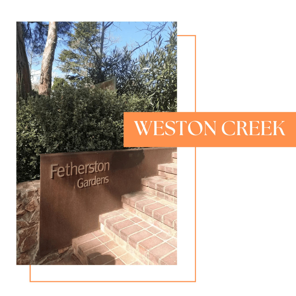 Signage for Fetherston Gardens at Weston Creek, featuring brick steps and greenery in the background.